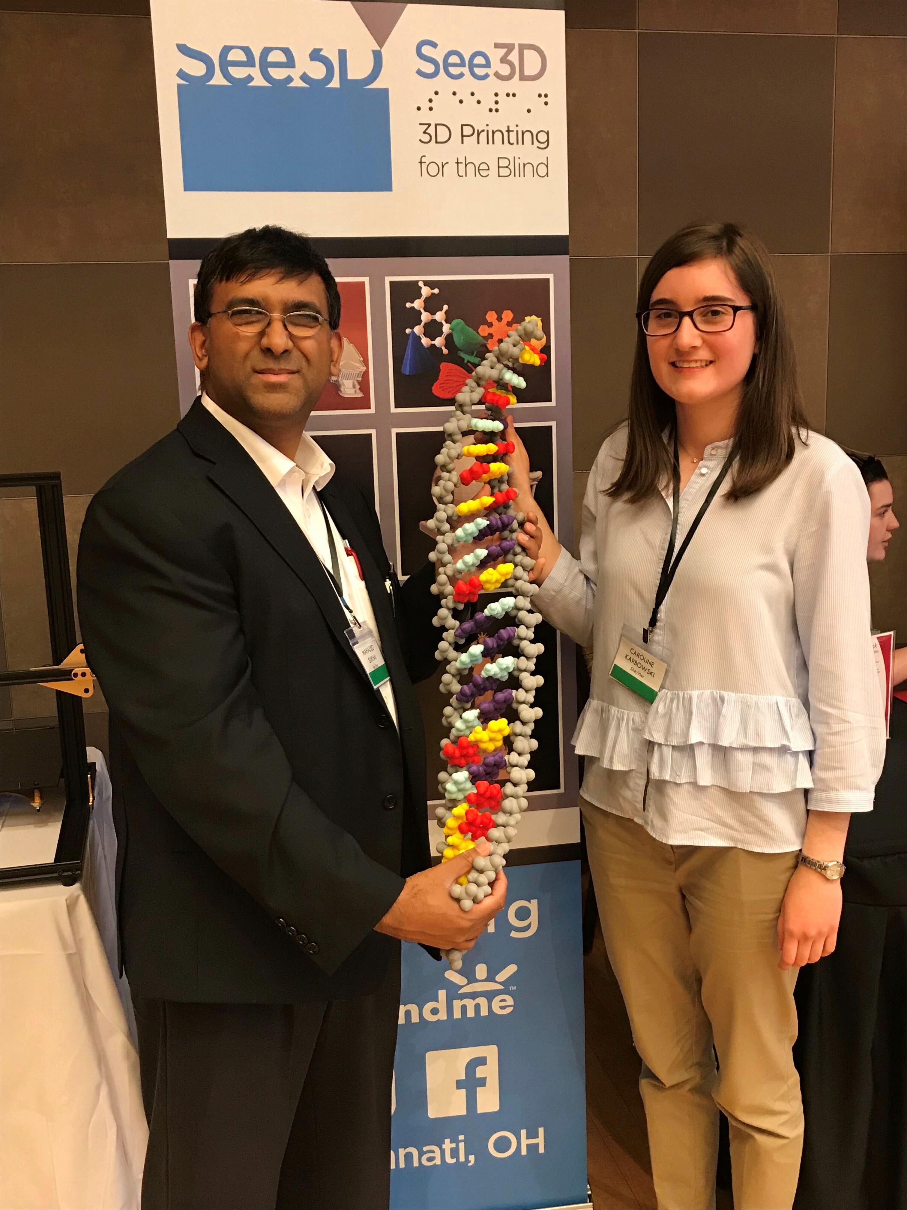 A picture of our CEO Caroline Karbowski with Dr. Sukhai holding a multi colored 3-D model of DNA